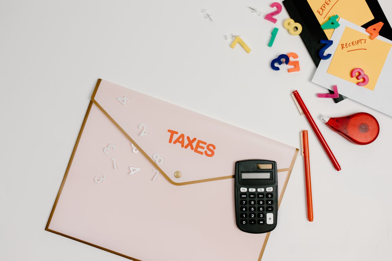 Flat lay of a tax preparation workspace with calculator, envelope, and colorful numbers.