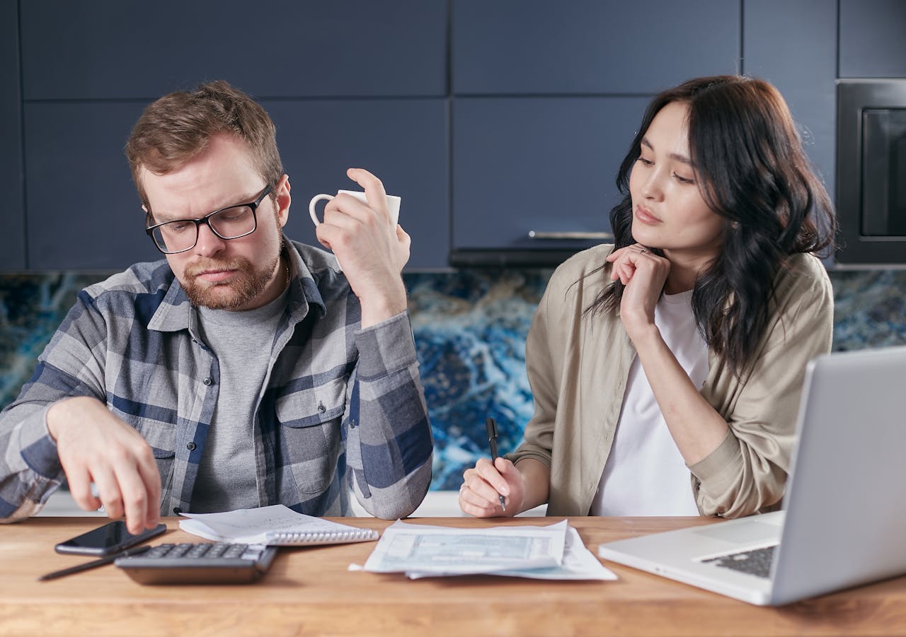 A focused young couple reviewing documents and managing their budget at home, showcasing modern financial challenges.